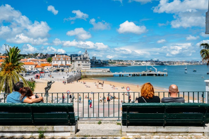 a person sitting on a bench next to a body of water