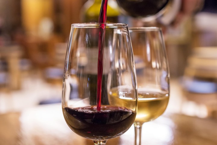 a glass of wine sitting on top of a wooden table