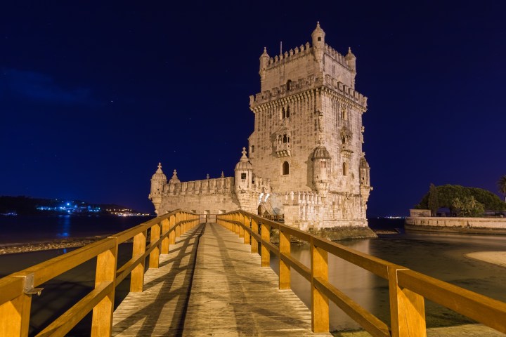 a castle on top of a wooden fence with Belém Tower in the background