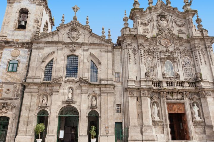 Ornate stone church facade with statues and blue sky background.