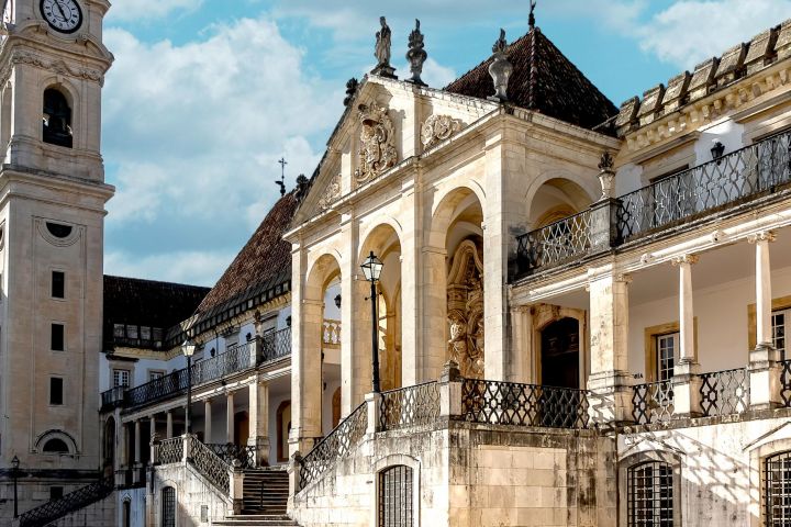 Ornate historic building with arches and clock tower under a blue sky with clouds.
