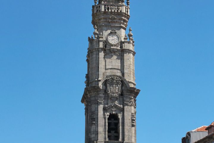 Tall stone clock tower with ornate details against a clear blue sky.