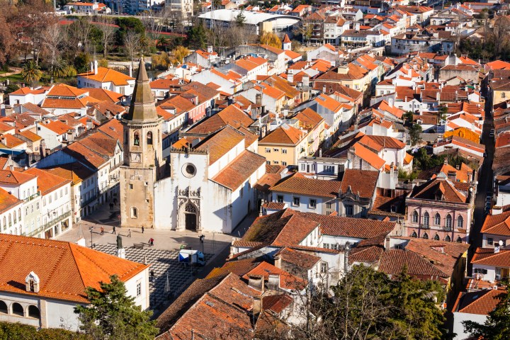 Aerial view of a historic town with a church and orange-roofed buildings.