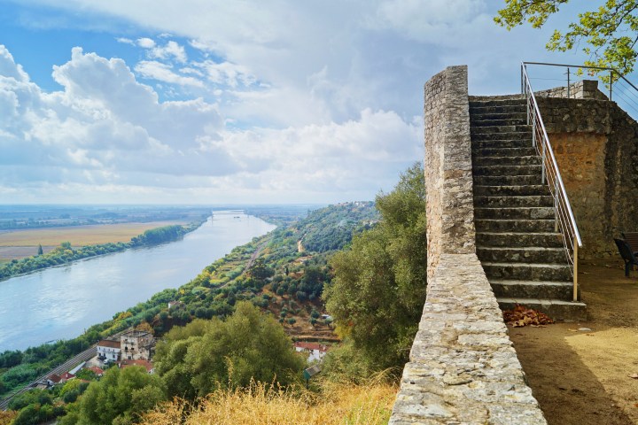 Stone staircase next to river valley with cloudy sky and distant landscape.