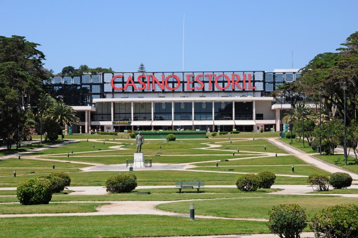 Front view of Casino Estoril with landscaped gardens and clear blue sky.