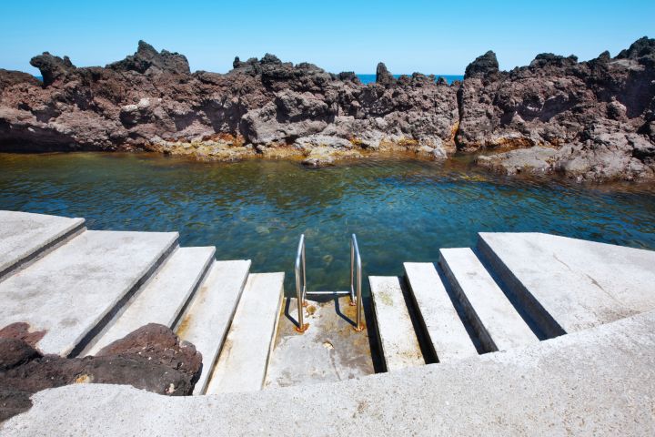 Concrete steps with railing leading into rocky tidal pool.