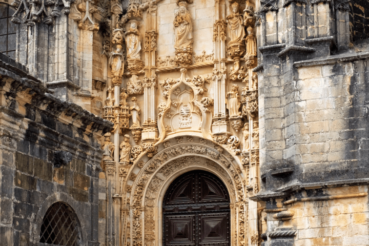 Intricate stone carvings surround an ornate wooden door on a historic building.