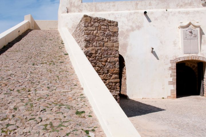 Fortress with a flag, stone path, and blue sky.