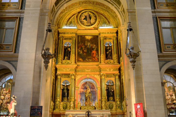 Ornate church altar with religious paintings and gold accents, flanked by candles.