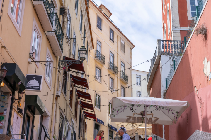 Outdoor cafe on narrow street with red and beige buildings and people dining.