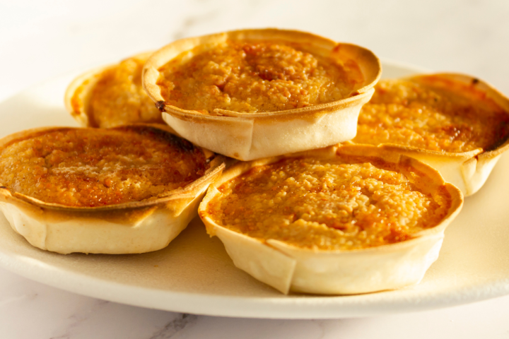 Plate of mini caramel tarts on a marble table.