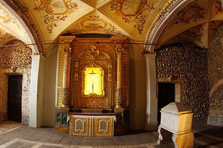 Ornate chapel with golden altar, vaulted ceiling, and stone tomb.