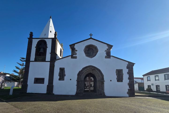 White church with bell tower under clear blue sky on a sunny day.