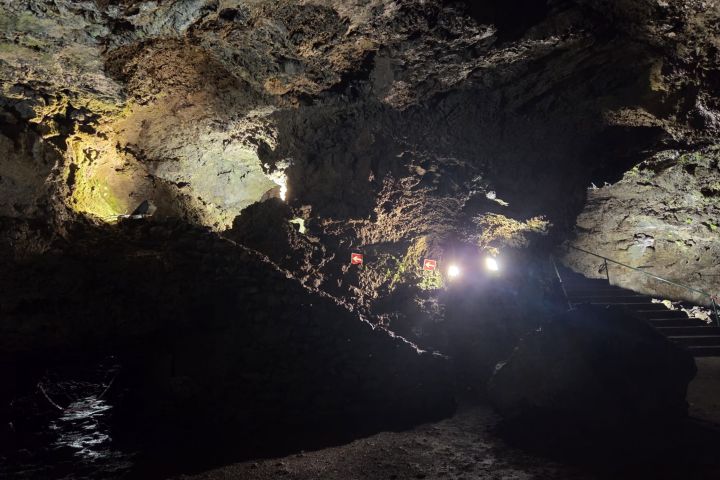 Dimly lit rocky cave interior with steps and light fixtures.