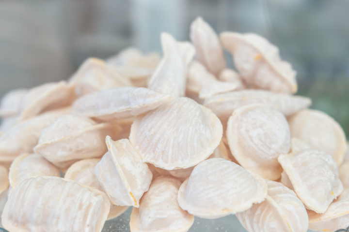 Close-up of white, flour-dusted pasta shells on a glass plate.