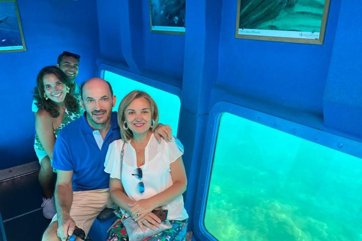Four people in a blue-themed room with underwater views.