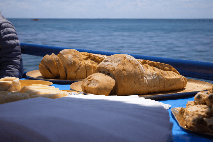 Bread loaves on a table by the sea with blue sky in background.
