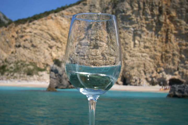 Wine glass with beach and cliffs in background.