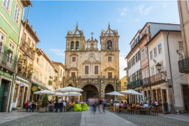 Historic cathedral with twin towers in a lively plaza with cafes.