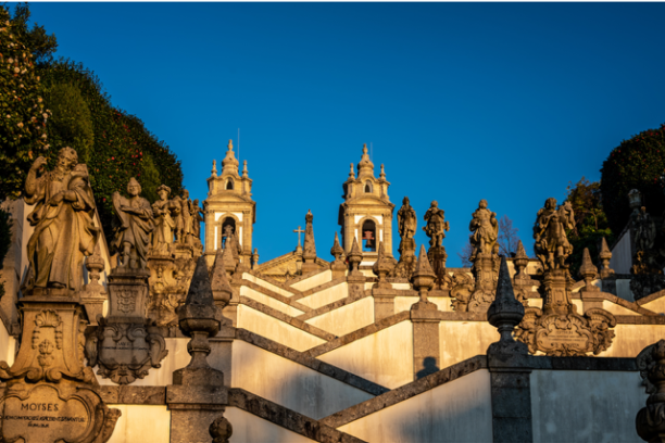 Staircase with ornate statues and towers against a clear blue sky.