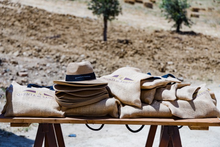 Stack of straw hats and burlap bags on a wooden table outdoors.